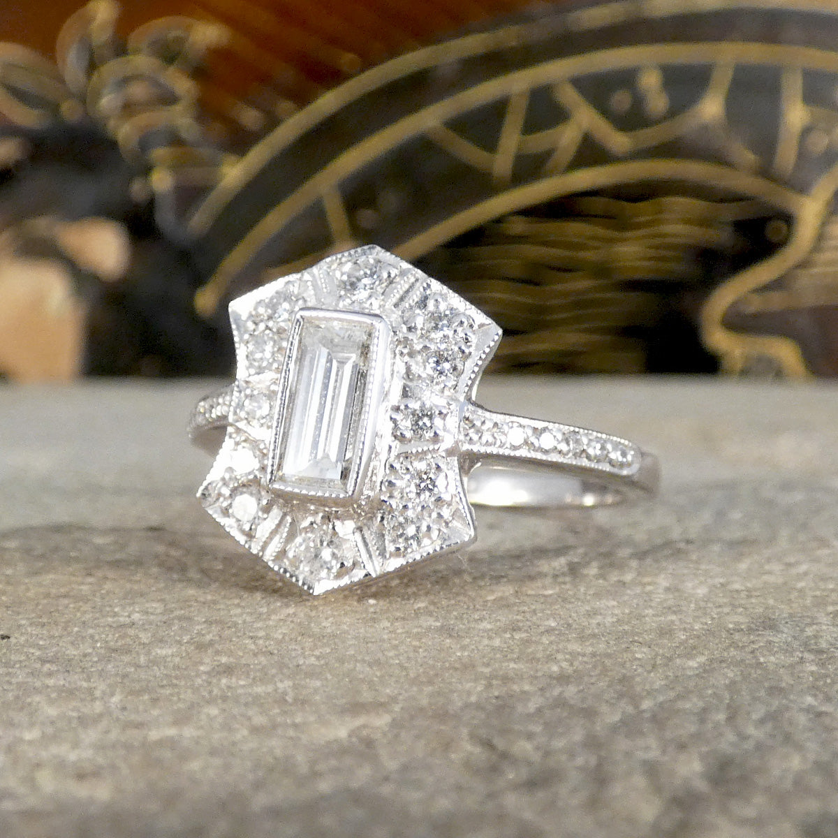 Silver coloured cluster ring with a diamond on a stone surface
