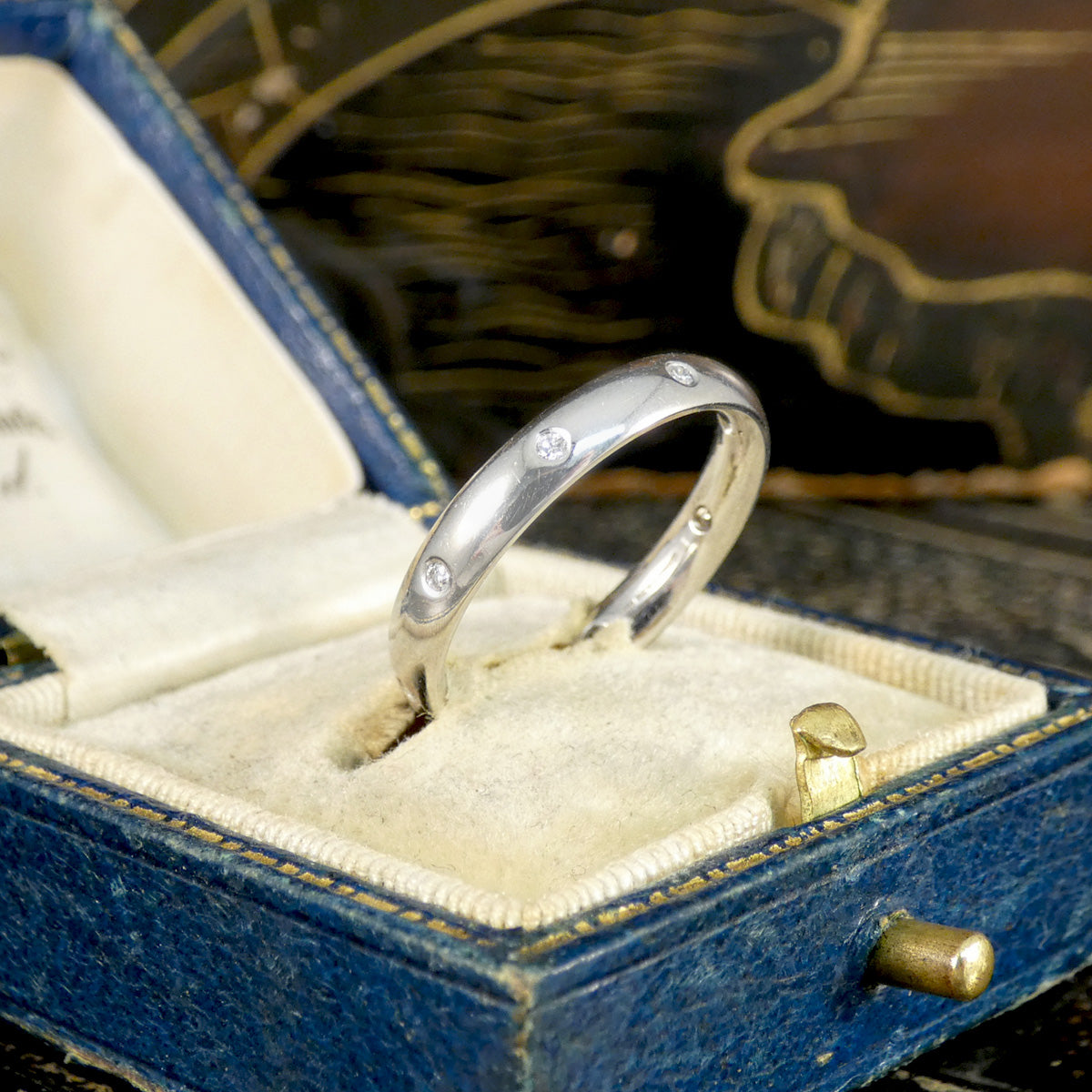 Silver ring with small diamonds in a blue jewelry box