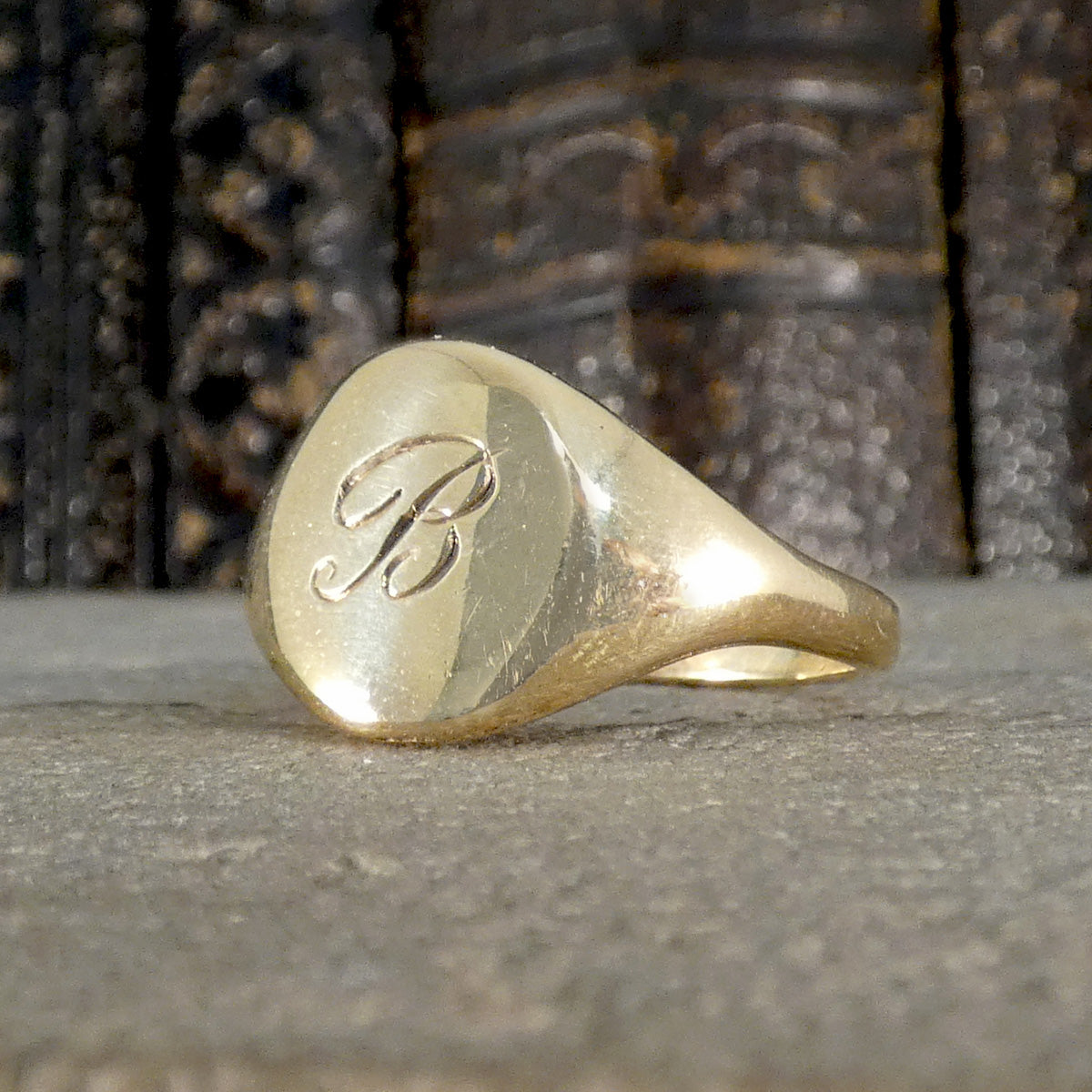 Gold ring with a monogram on a textured surface