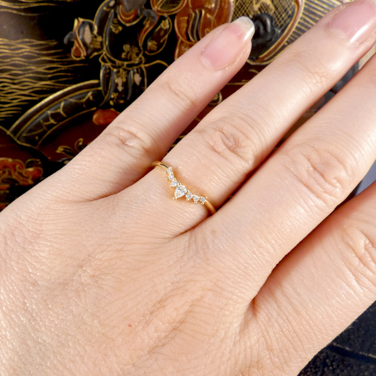 Hand wearing a gold ring with a diamond on a decorative background