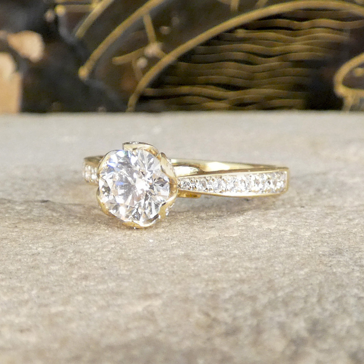 Gold ring with a large diamond and smaller diamonds on the band, set against a neutral background.