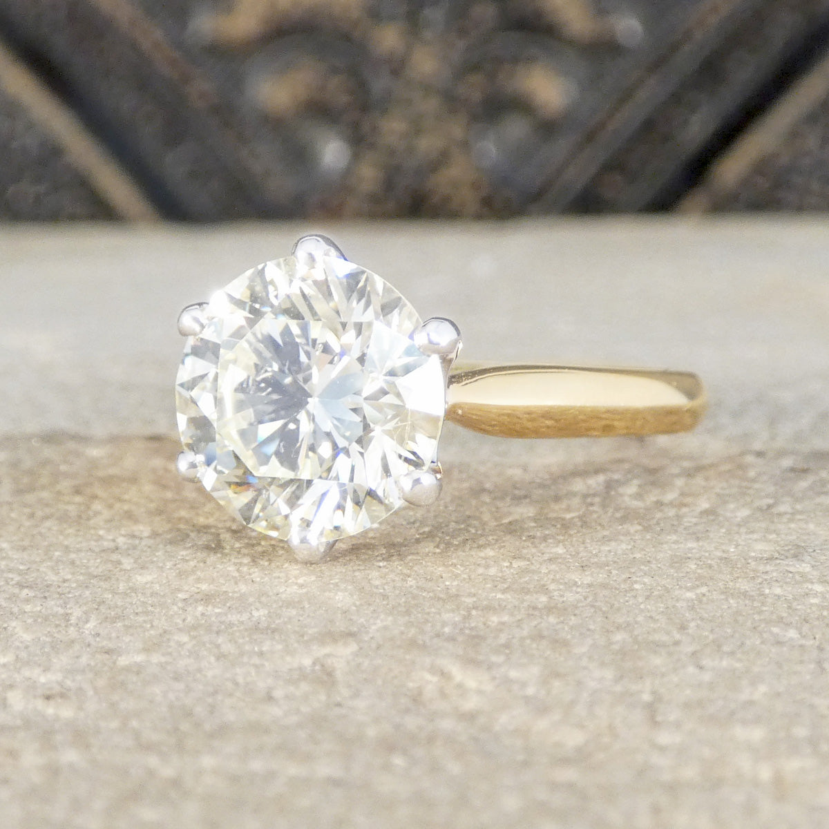 Gold ring with a large diamond on a textured surface
