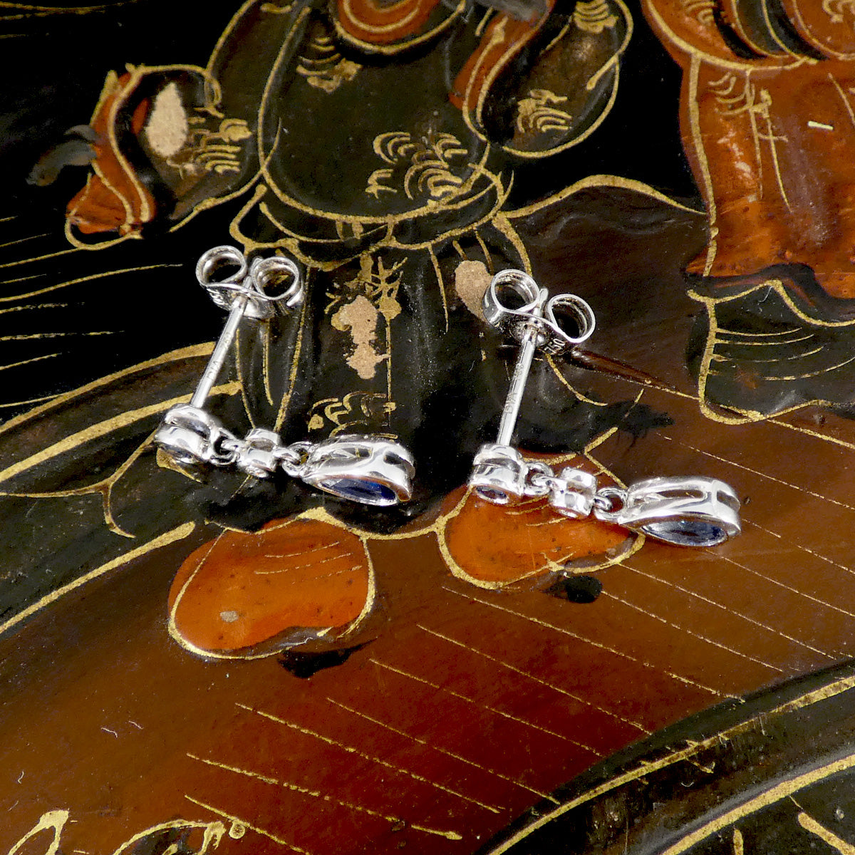 white gold earrings with gemstones on a decorative background