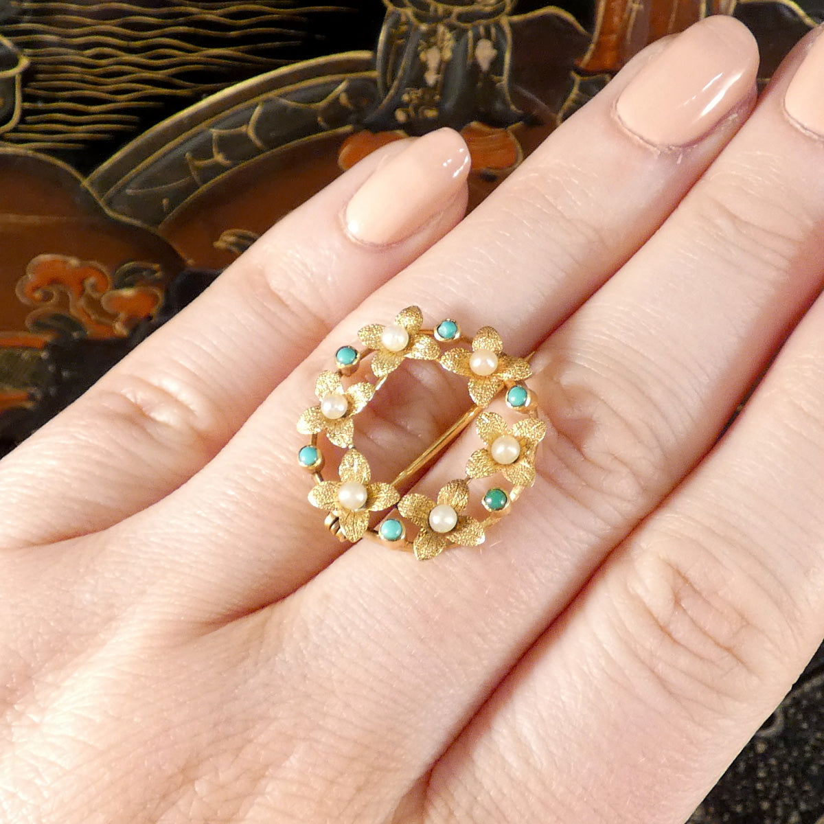 Edwardian Seed Pearl and Turquoise Wreath Brooch in 15ct Yellow Gold displayed on hand for size reference.