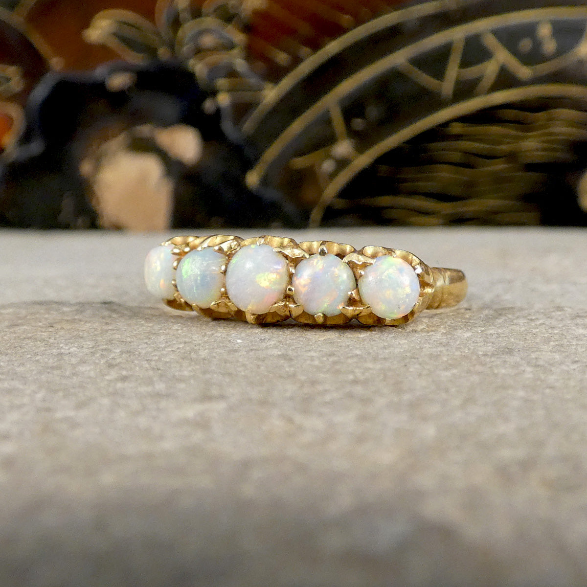Gold ring with opal stones on a textured surface