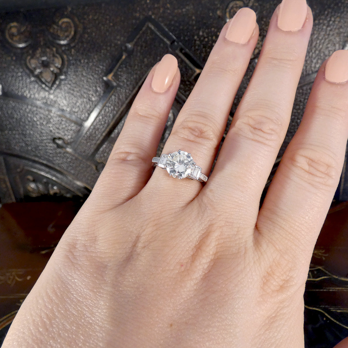 Hand wearing a diamond ring with a dark background