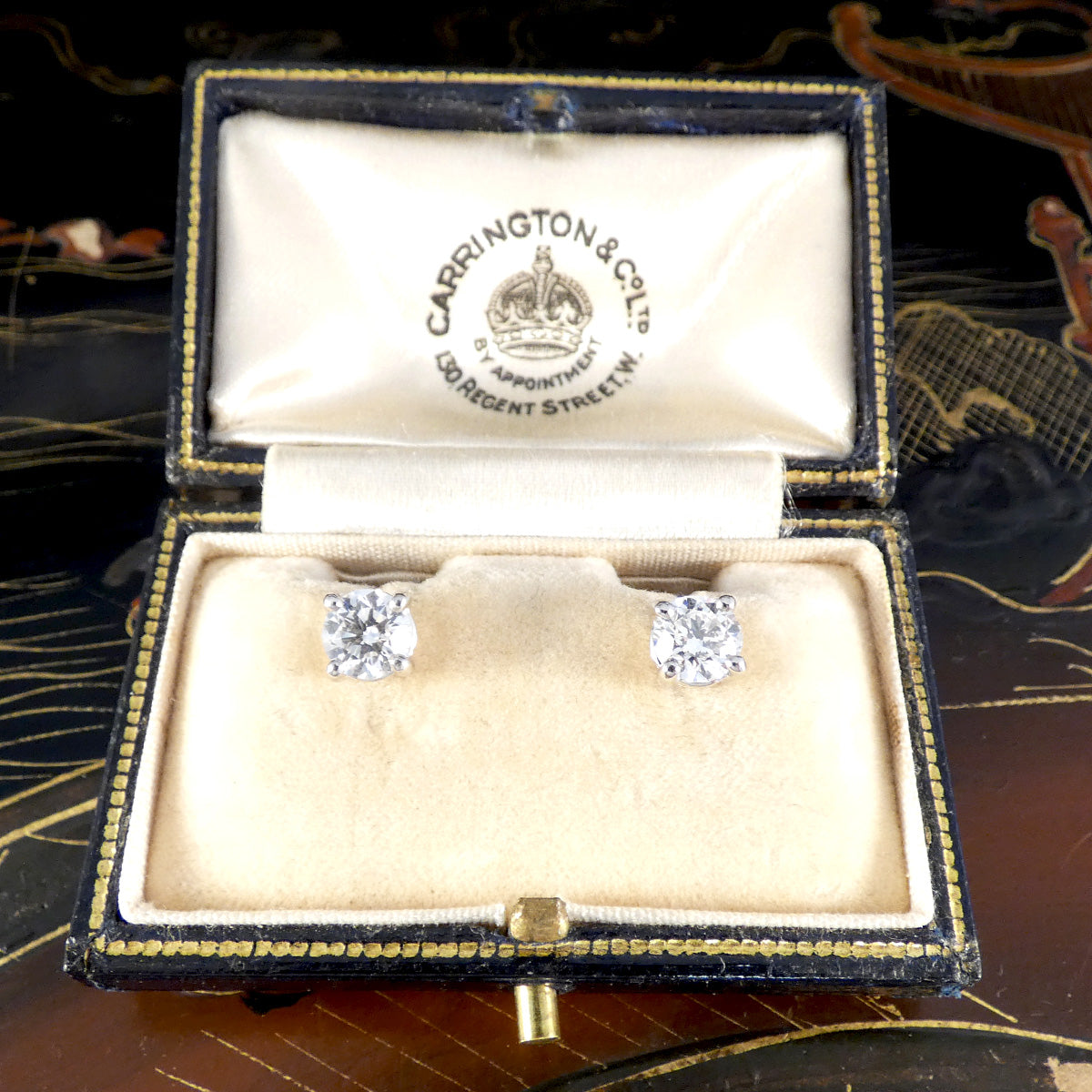 Diamond earrings in a Carringtons & Co box on a decorative background. 1.40ct total, G/VS grading natural diamonds in Platinum.