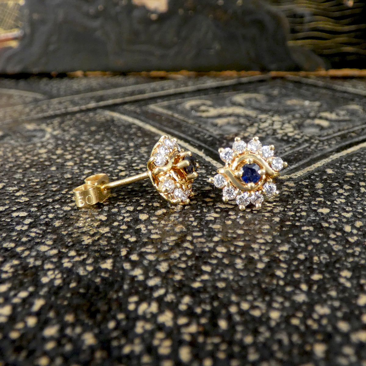 Gold earrings with gemstones on a textured surface