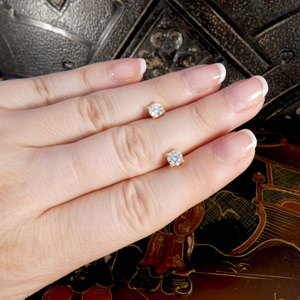 A pair of Diamond stud earrings displayed on the hand for size reference. GIA certed diamonds G/VS.
