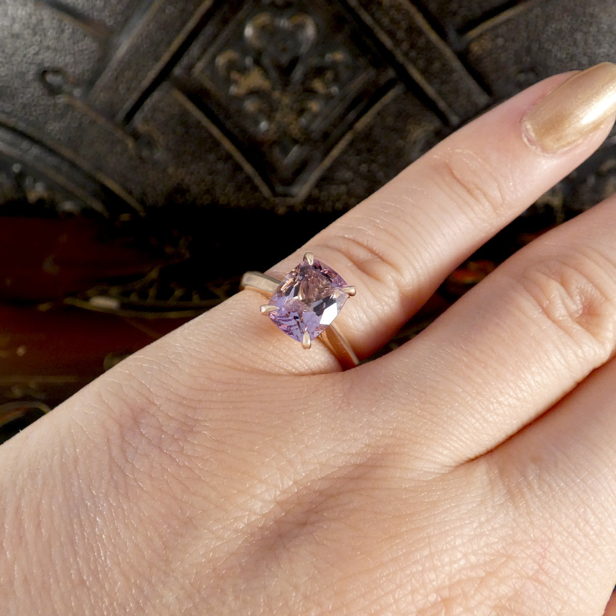 Ring with a purple gemstone on a finger against a dark background