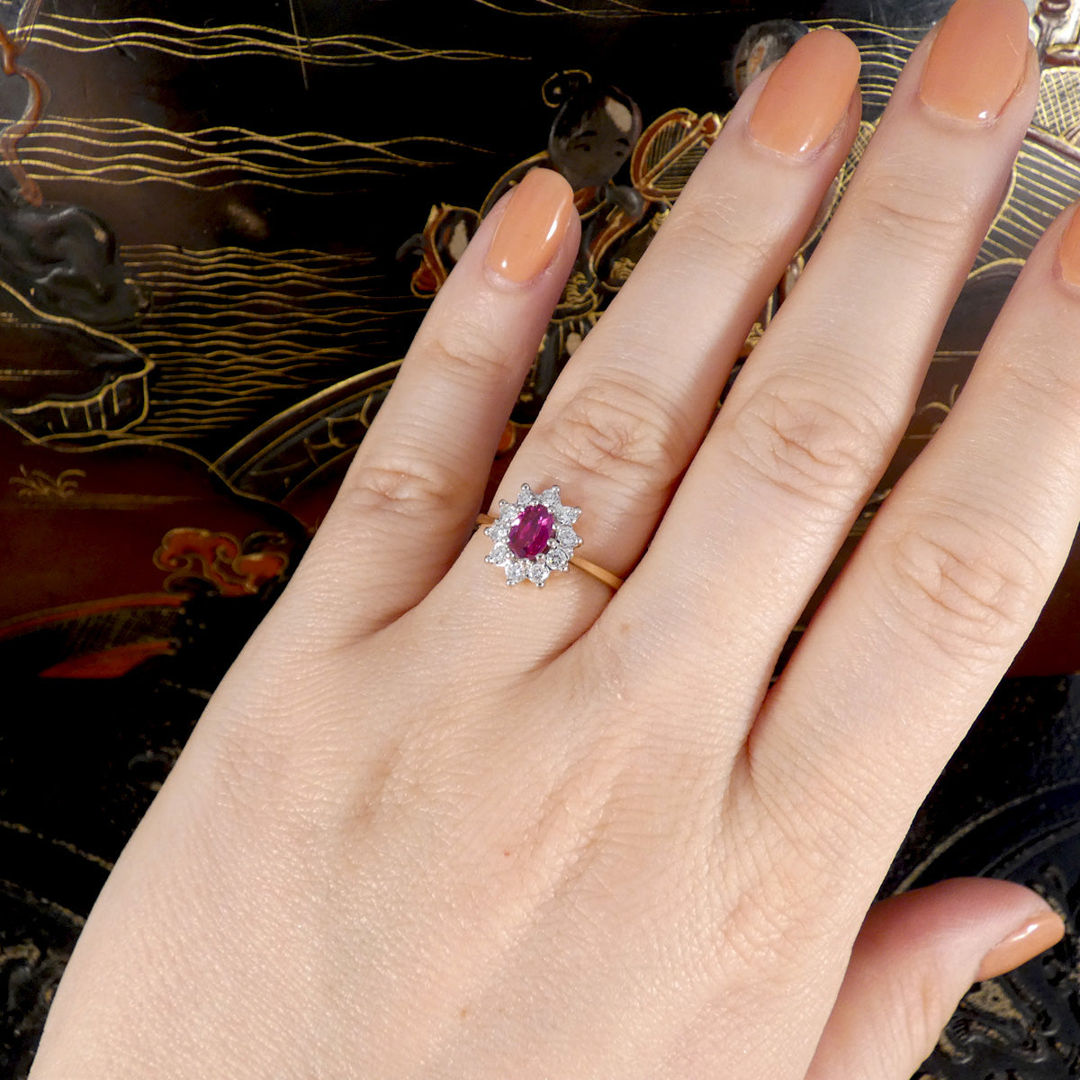 Hand wearing a ring with a ruby gemstone on a decorative background
