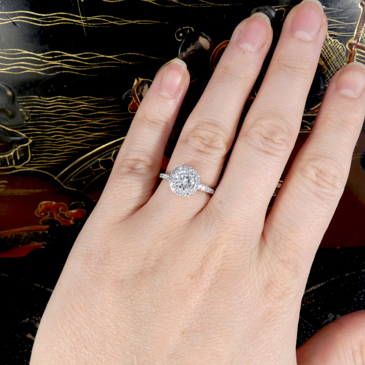 Hand wearing a diamond ring with a decorative background