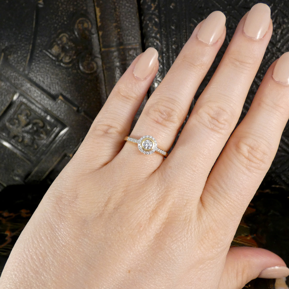 A diamond halo cluster ring shown on the ring finger to show what it would look like when worn as engagement ring.