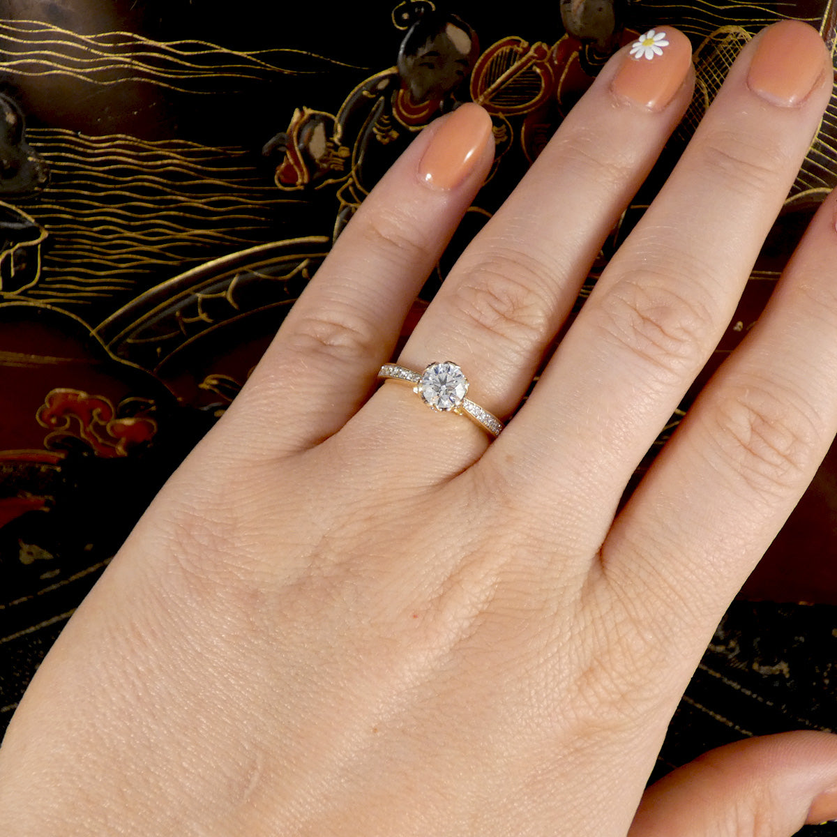 Hand wearing a diamond ring with a decorative background