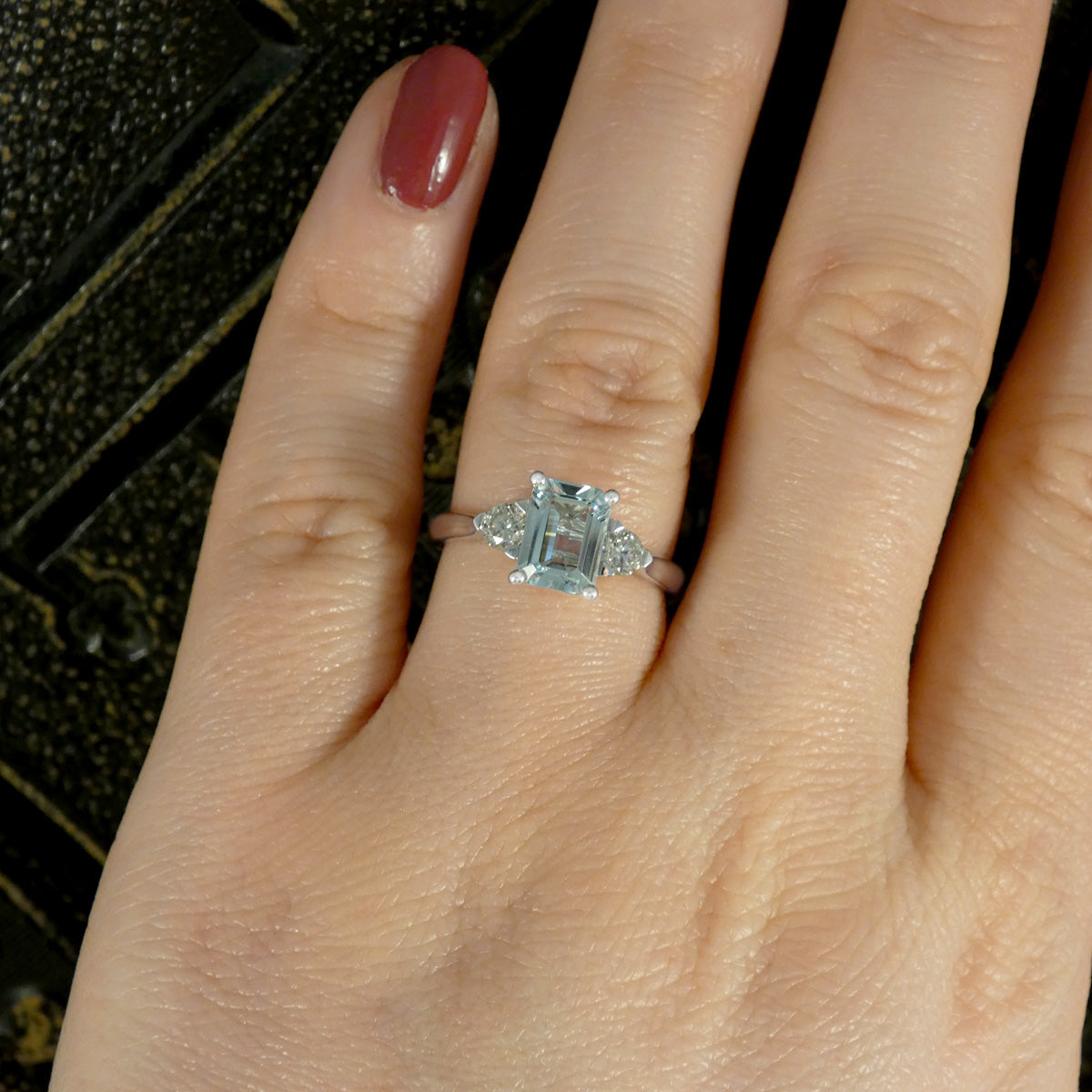 Back view of Modern Emerald Cut Aquamarine and 0.35ct Diamond Three Stone Ring in Platinum. Slightly tapered shoulders leading to. plain polished band and slight wedfit design for a perfect engagement ring. Shown worn on the finger to see size and colour reference.