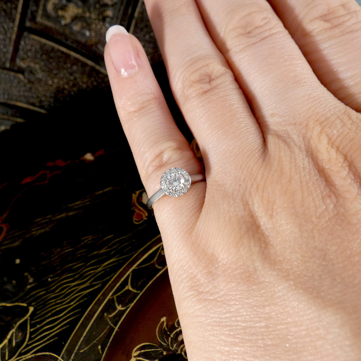 Close-up of a hand wearing a diamond ring with an intricate background