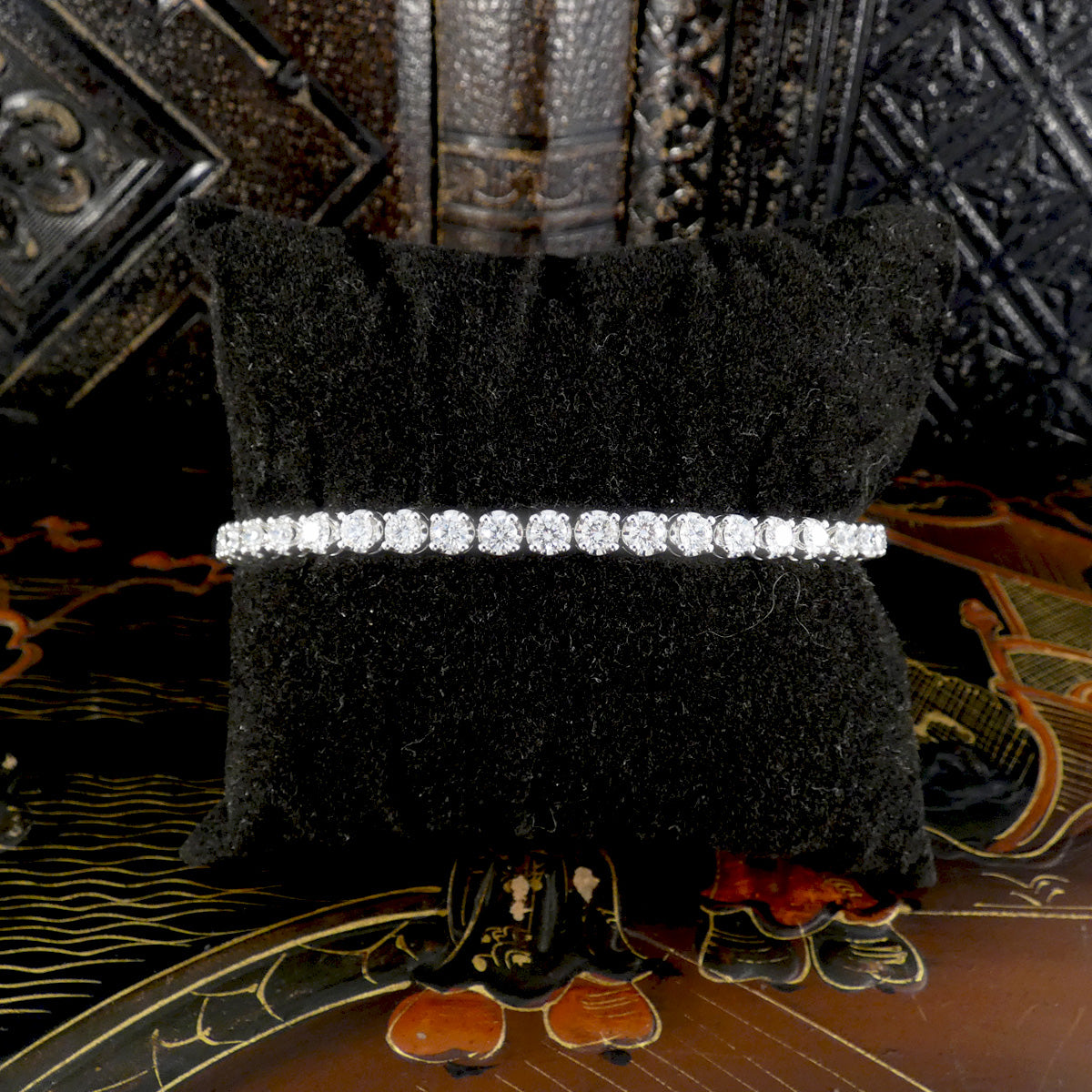Platinum diamond tennis bracelet displayed on black velvet cushion, showcasing a flawless line of brilliant round-cut diamonds in a secure four-claw setting, ideal for luxury fine jewelry collections.