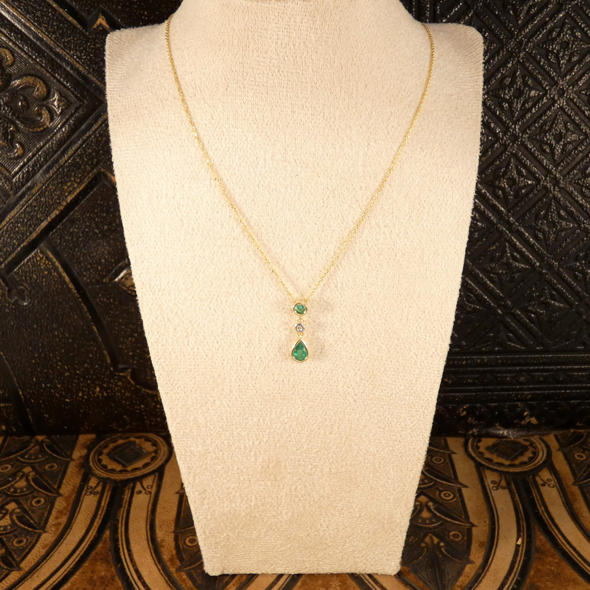 Modern Emerald and Diamond Bezel Set Drop Pendant Necklace in Yellow Gold shown on bust for size reference.