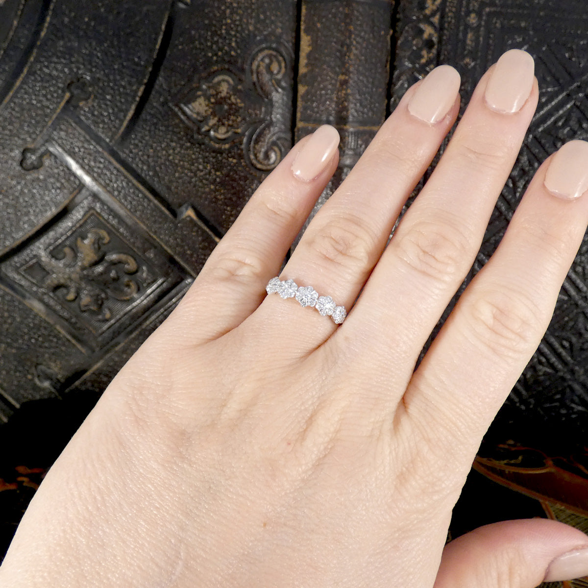 A beautiful diamond flower cluster half eternity ring shown on the finger.