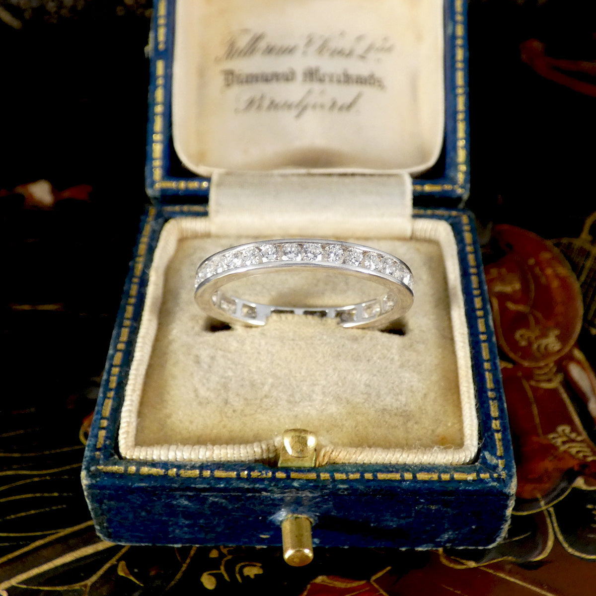 Diamond ring in a blue velvet box with gold accents on a decorative background