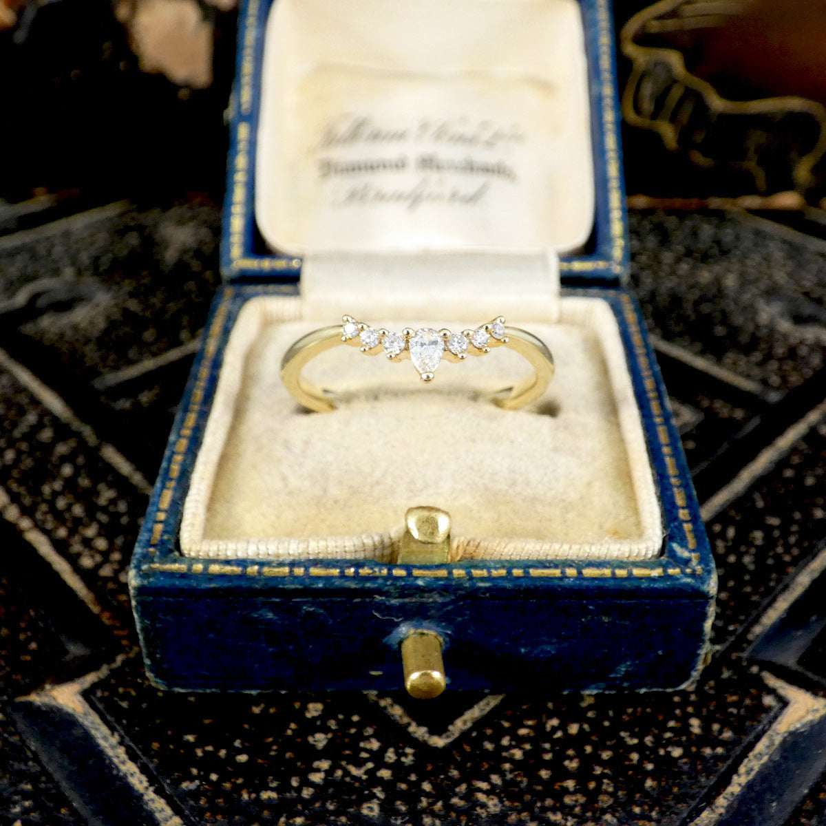 Gold ring with diamonds in a blue velvet box on a textured surface