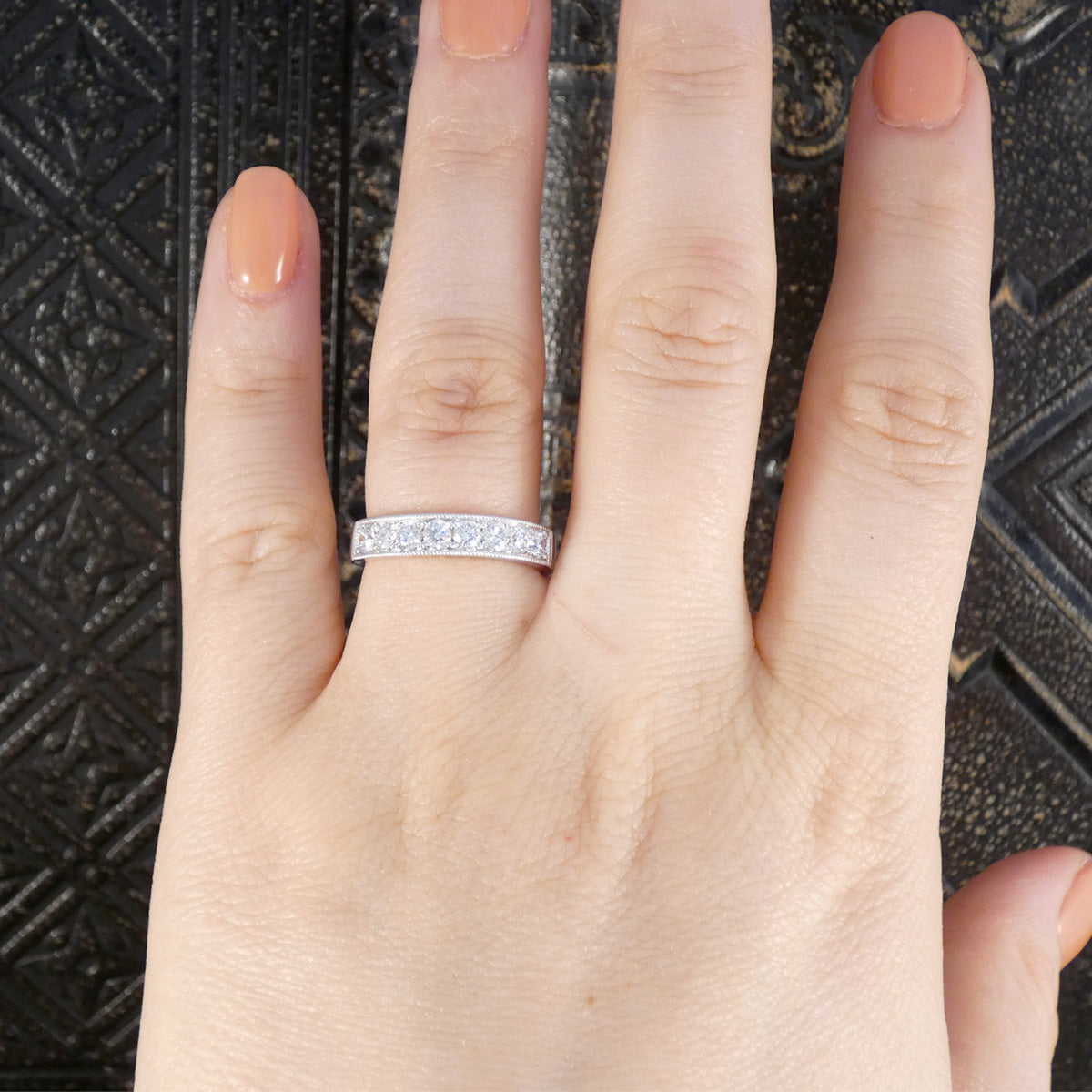 Hand wearing a diamond ring on a textured black background making the perfect wedding band.