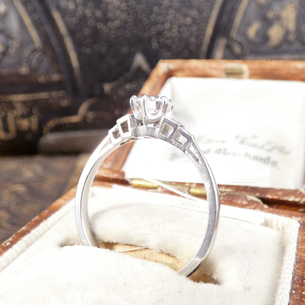 Side view of classic and beautiful diamond solitaire ring with diamond set shoulders.