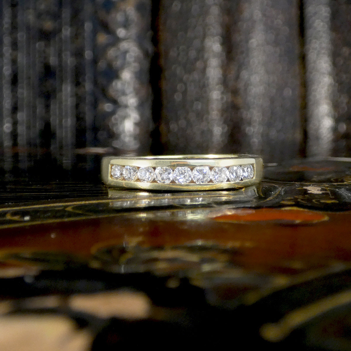 Gold ring with diamonds on a decorative surface showing full channel setting.