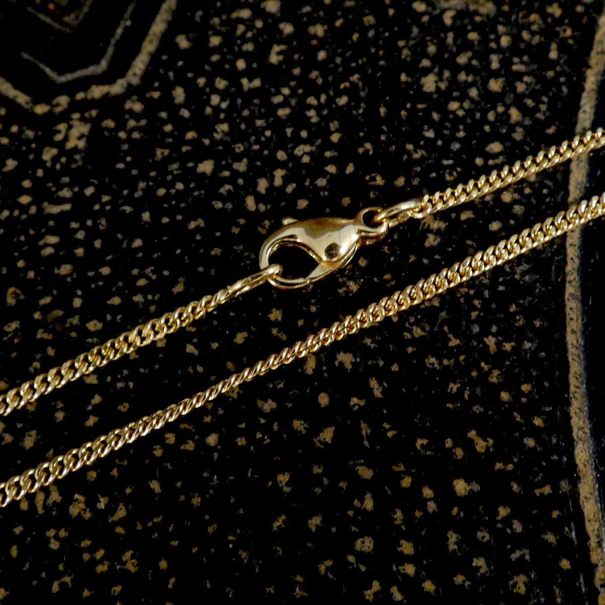 Gold chain with clasp on a textured black background