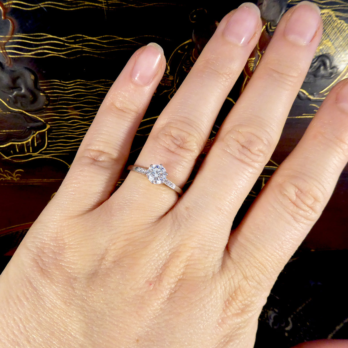 Hand wearing a diamond ring with a decorative background showing bright colour and certified diamond.