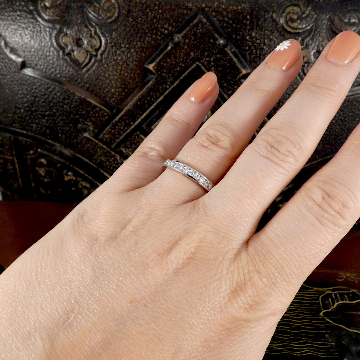 Hand wearing a diamond ring with a dark textured background