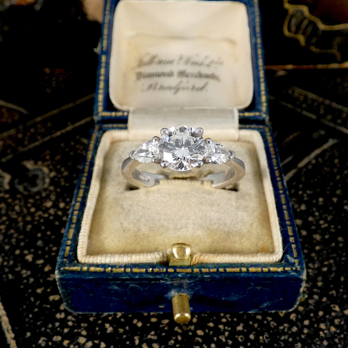 Diamond ring in a blue velvet box on a textured surface