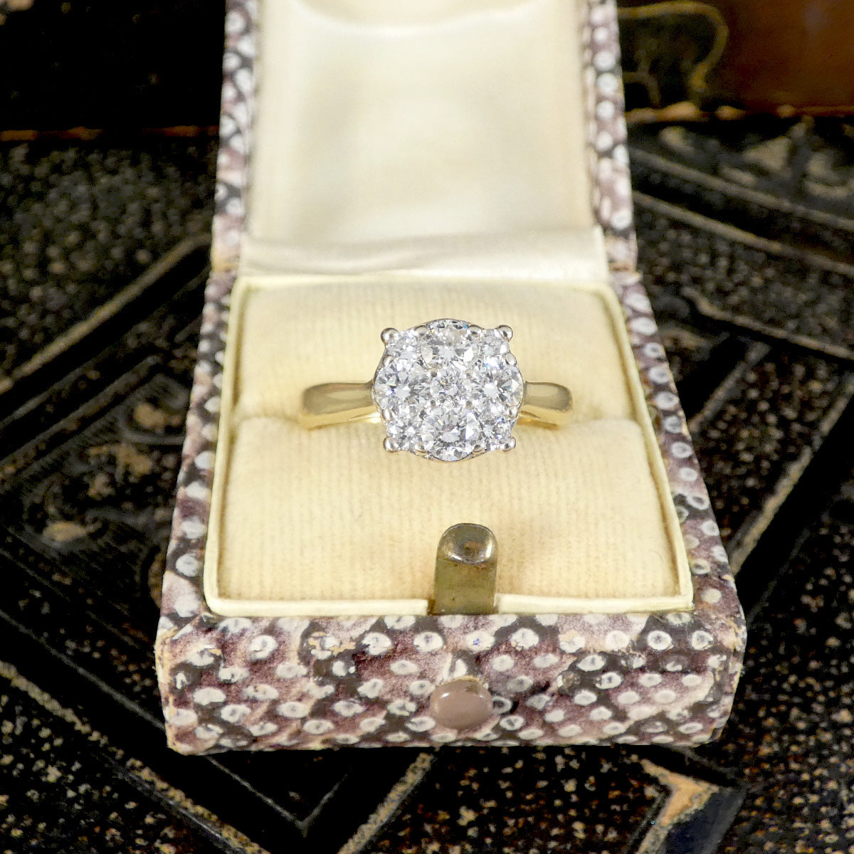 Diamond ring in an open jewelry box on a patterned surface