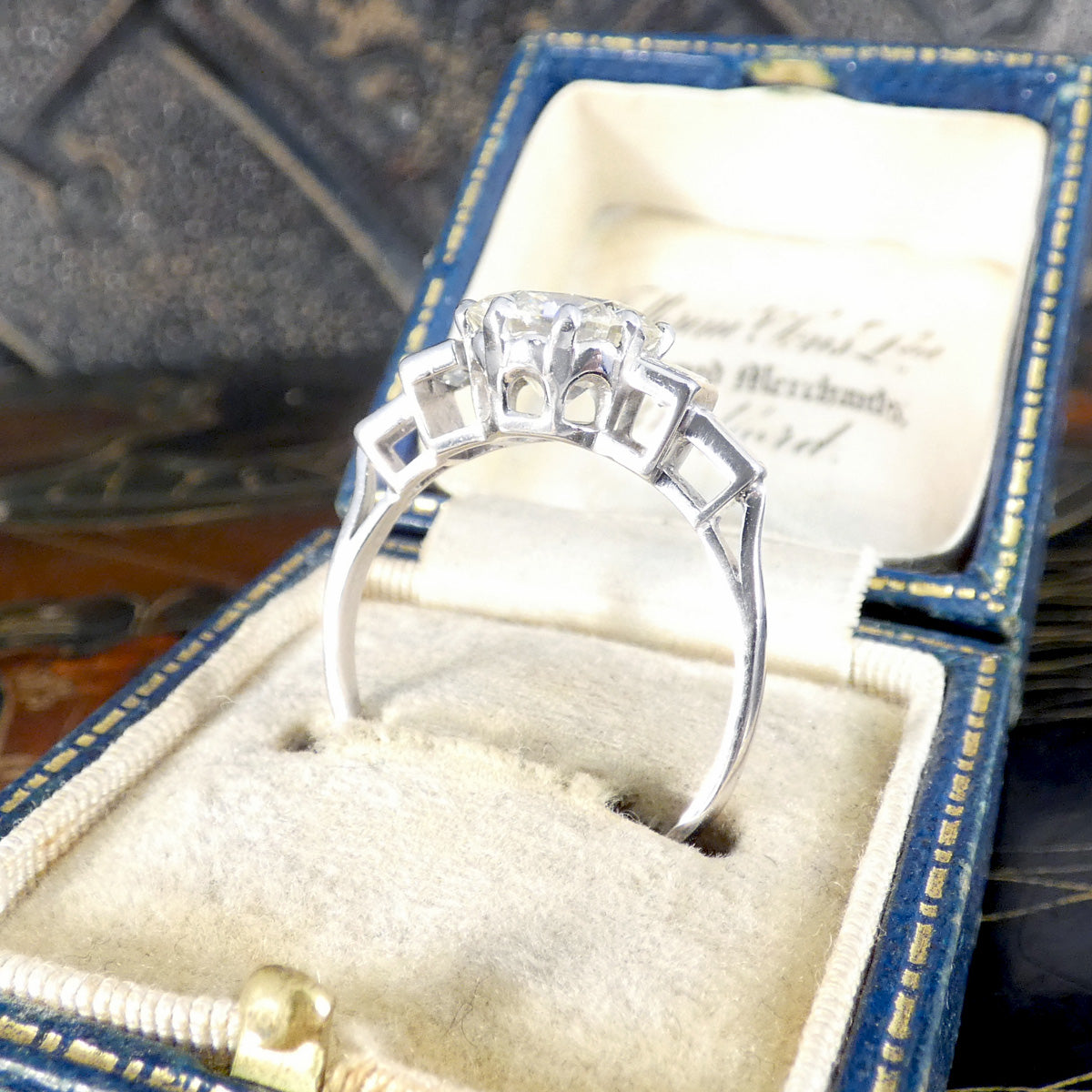 Silver ring with gemstones in a blue and gold jewelry box.