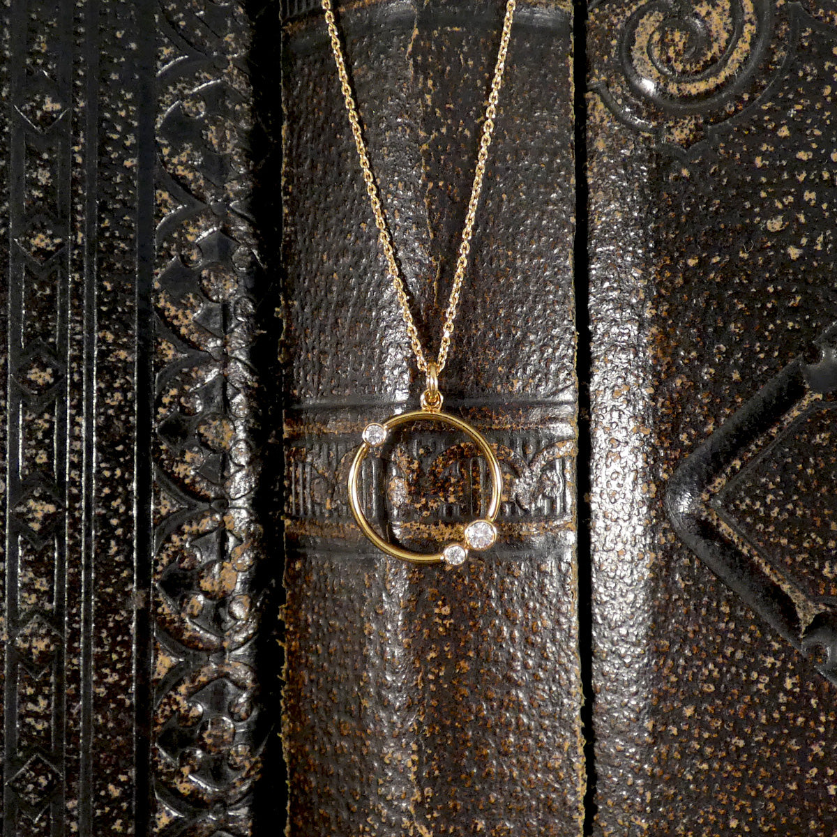 Gold necklace with a circular pendant on an ornate wooden surface
