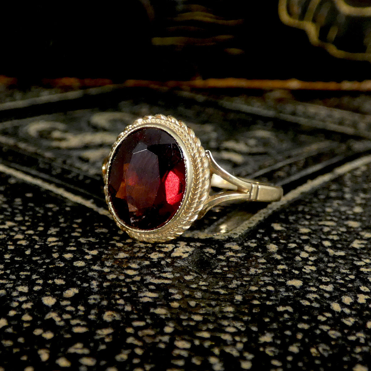 Vintage Gold ring with a red garnet gemstone on a textured surface