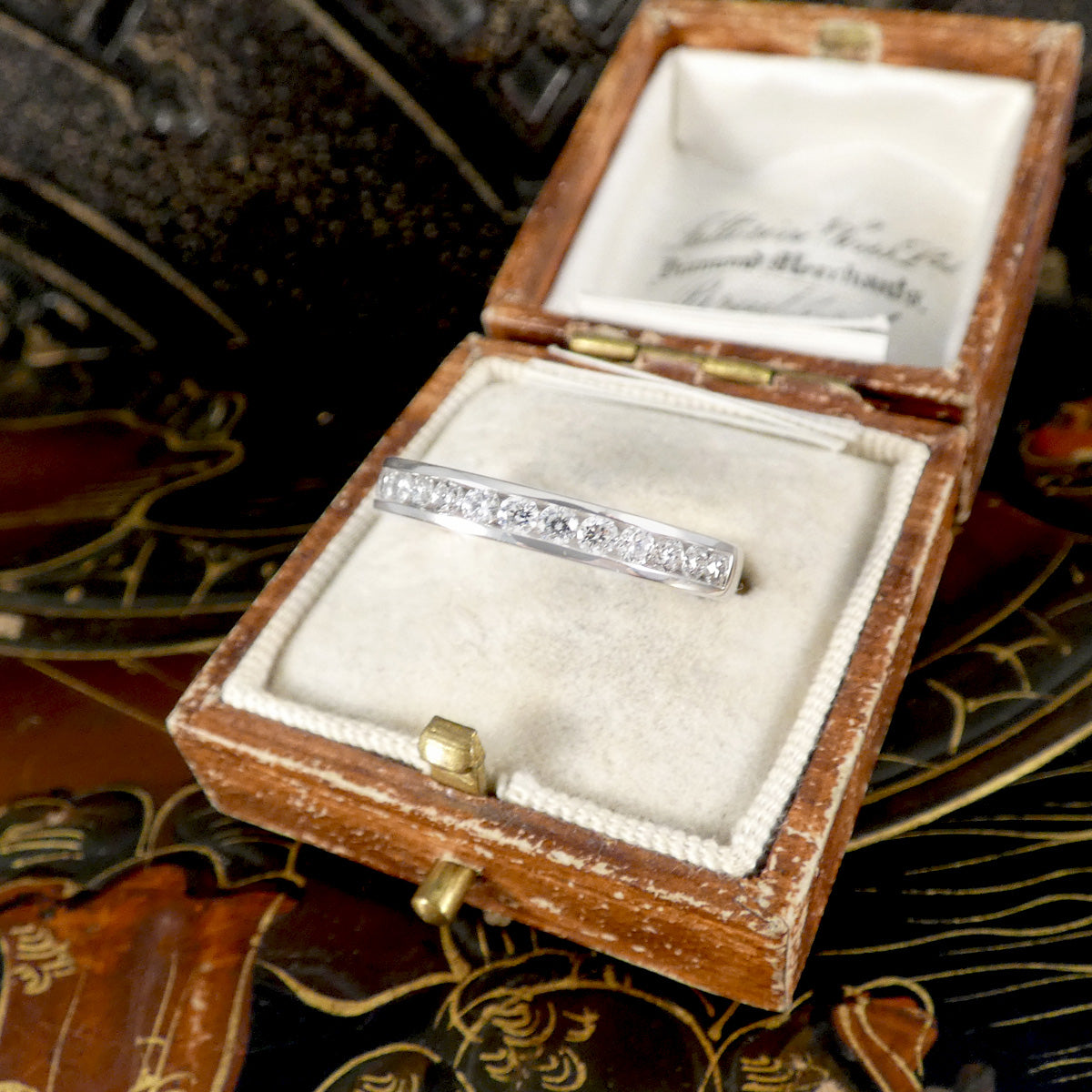 Silver ring in an open wooden jewelry box with a decorative background