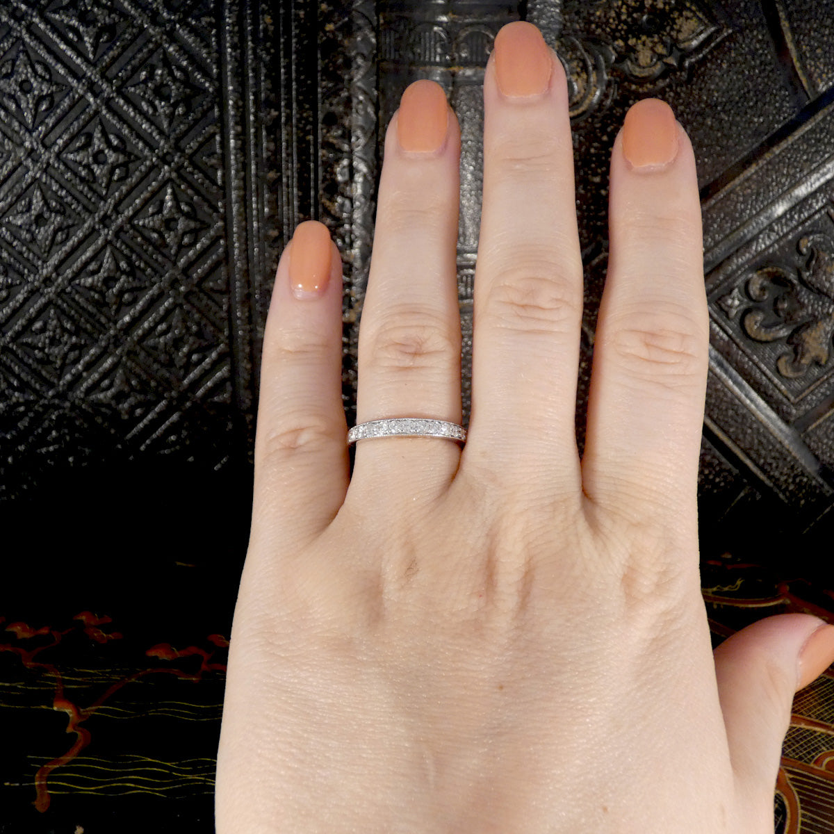 Hand wearing a diamond ring with a dark textured background