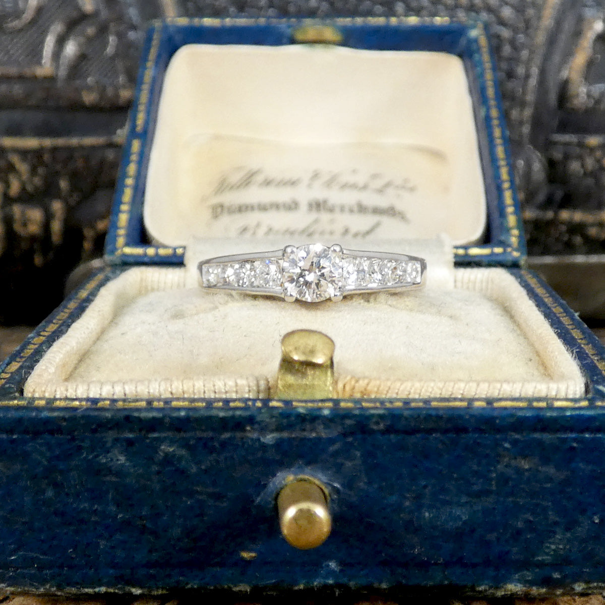 Diamond ring in a blue jewelry box with an engraved lid