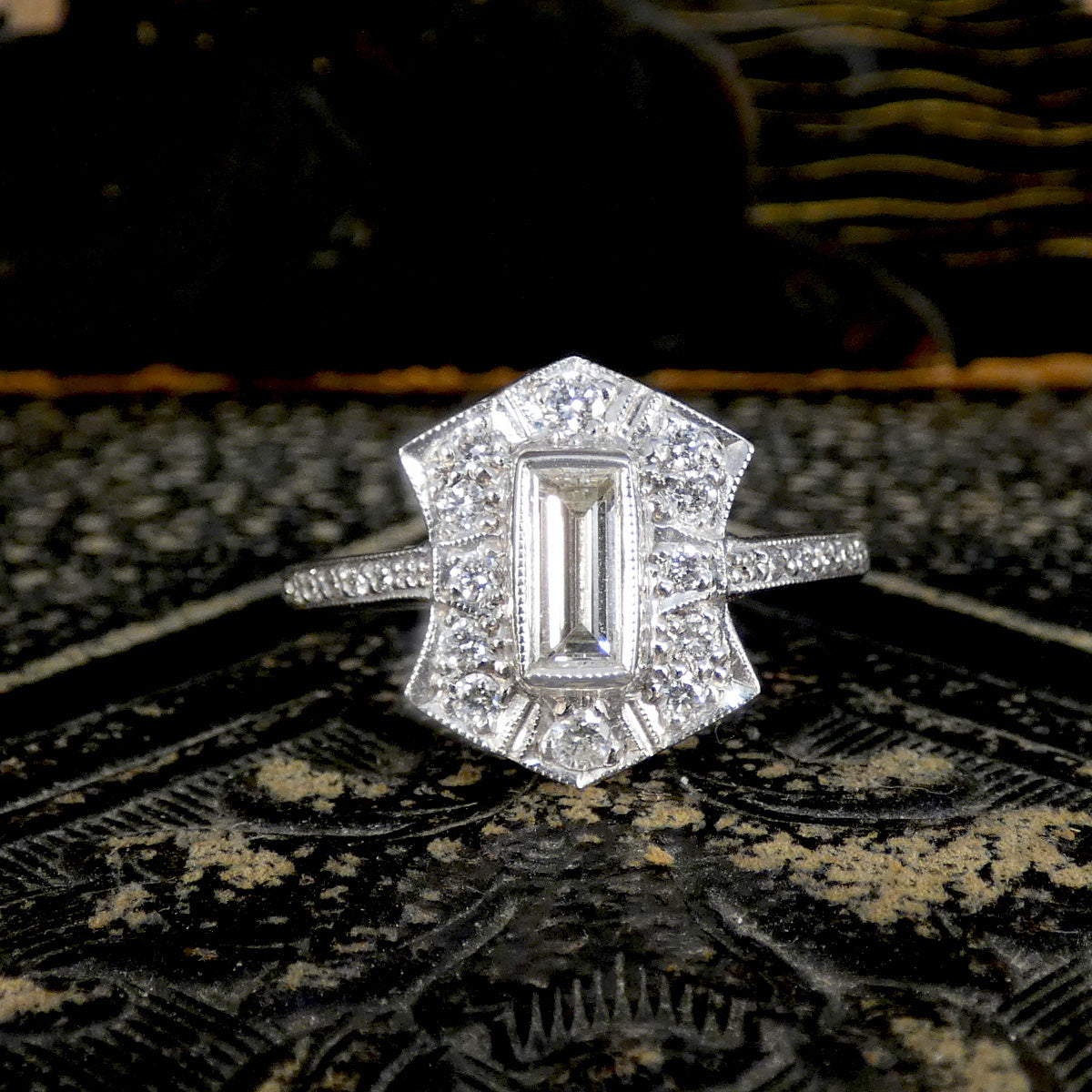 Diamond ring with a geometric design on a textured fabric background