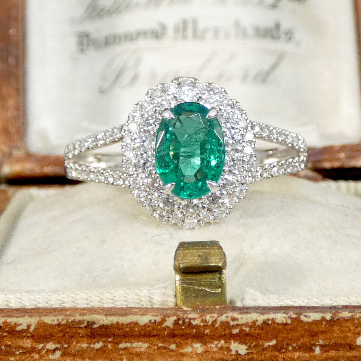 Emerald ring with diamond halo in an antique box