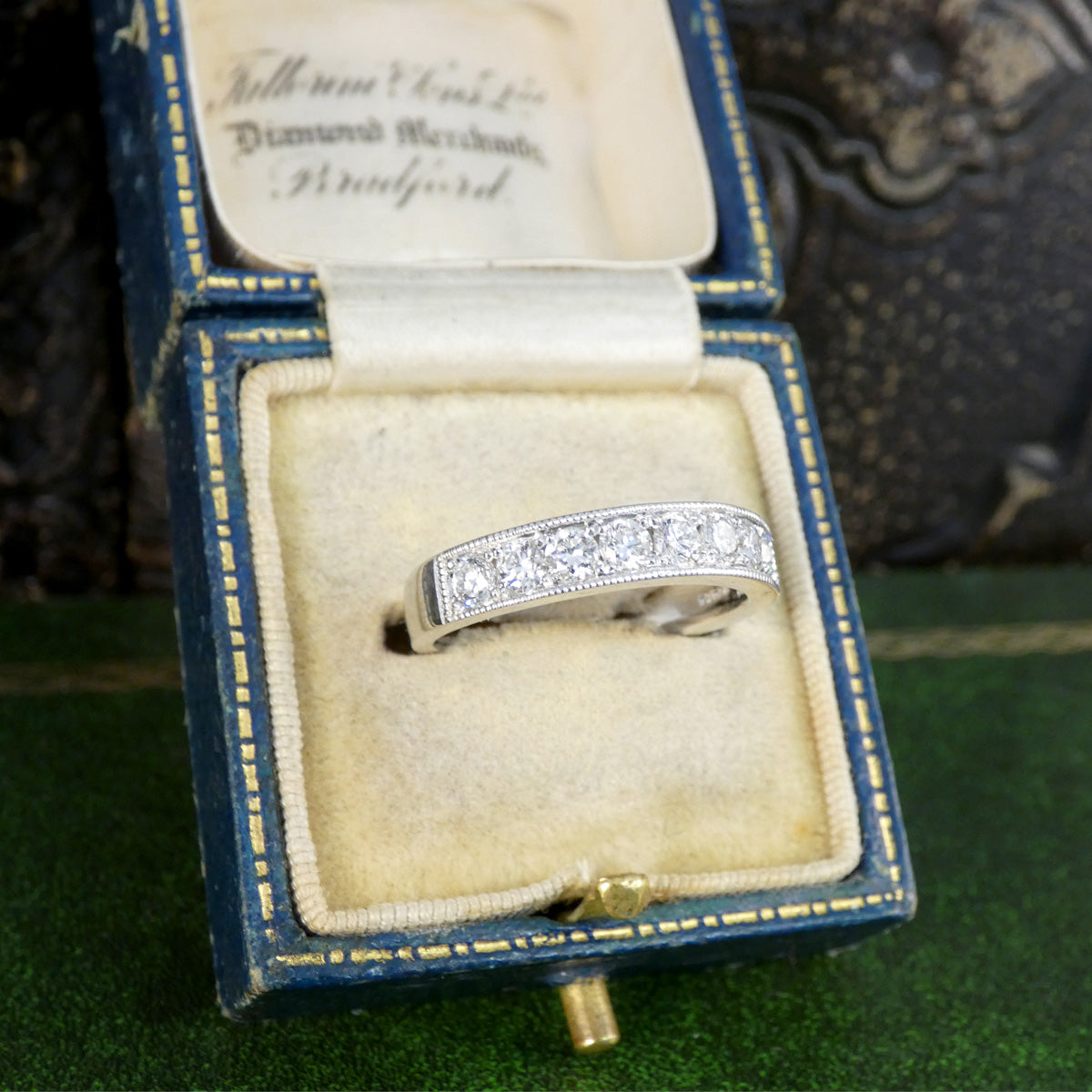Diamond ring in a blue jewelry box on a green surface