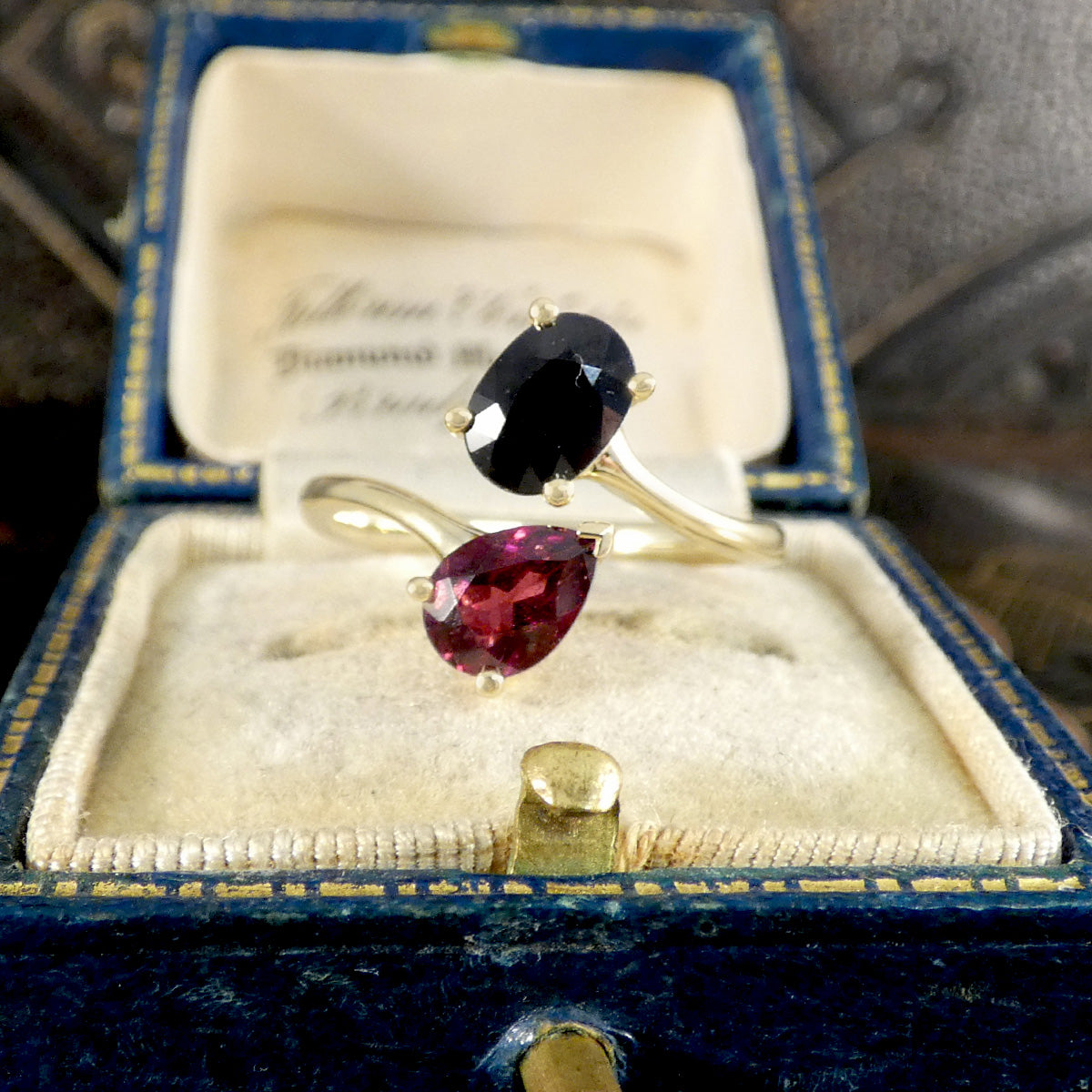 Two gemstone rings in a blue jewelry box with visible text.