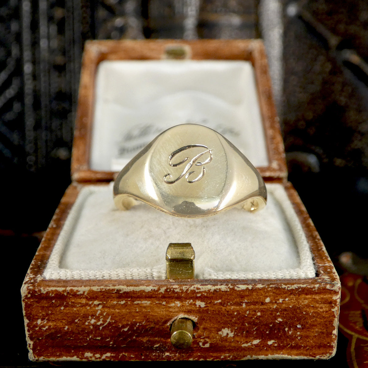 Gold ring with 'B' monogram in a wooden box
