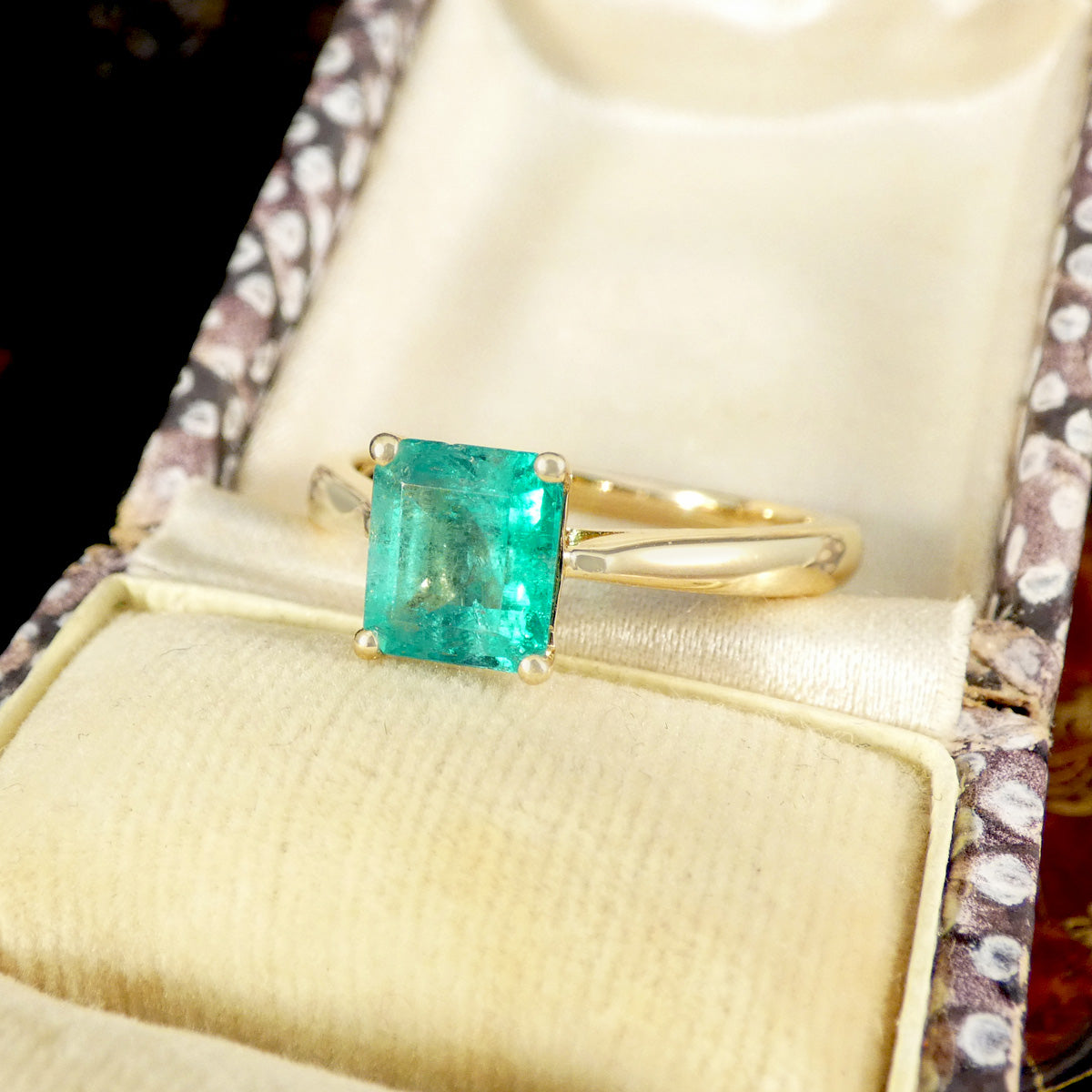 Gold ring with a green gemstone in a vintage box.