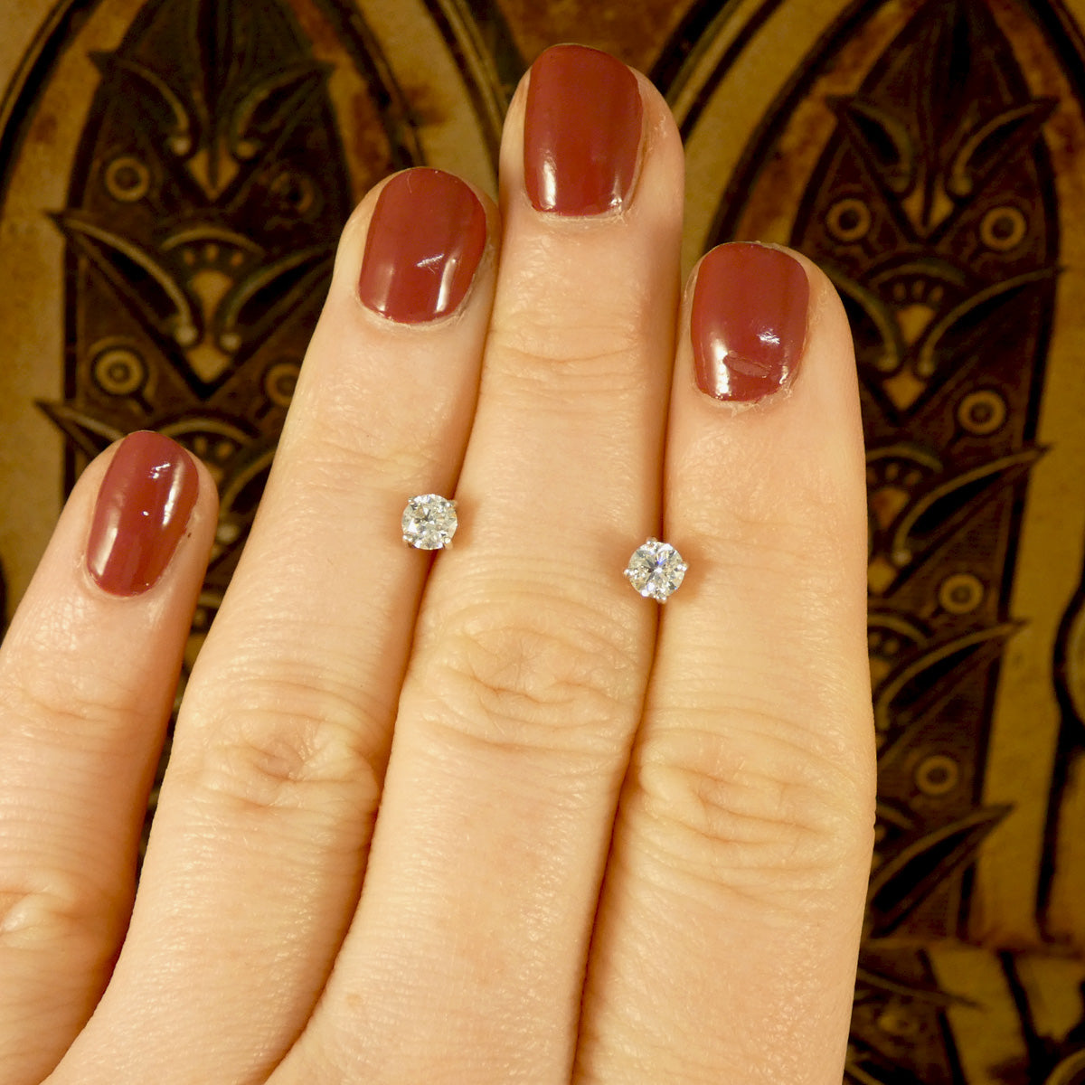 The GIA certed D colour diamond stud earrings without the halo cluster surround shown on the hand for size reference.