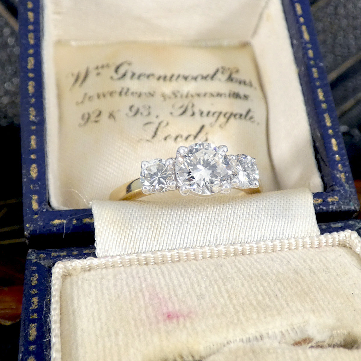 Diamond ring in a vintage jewelry box with engraved text