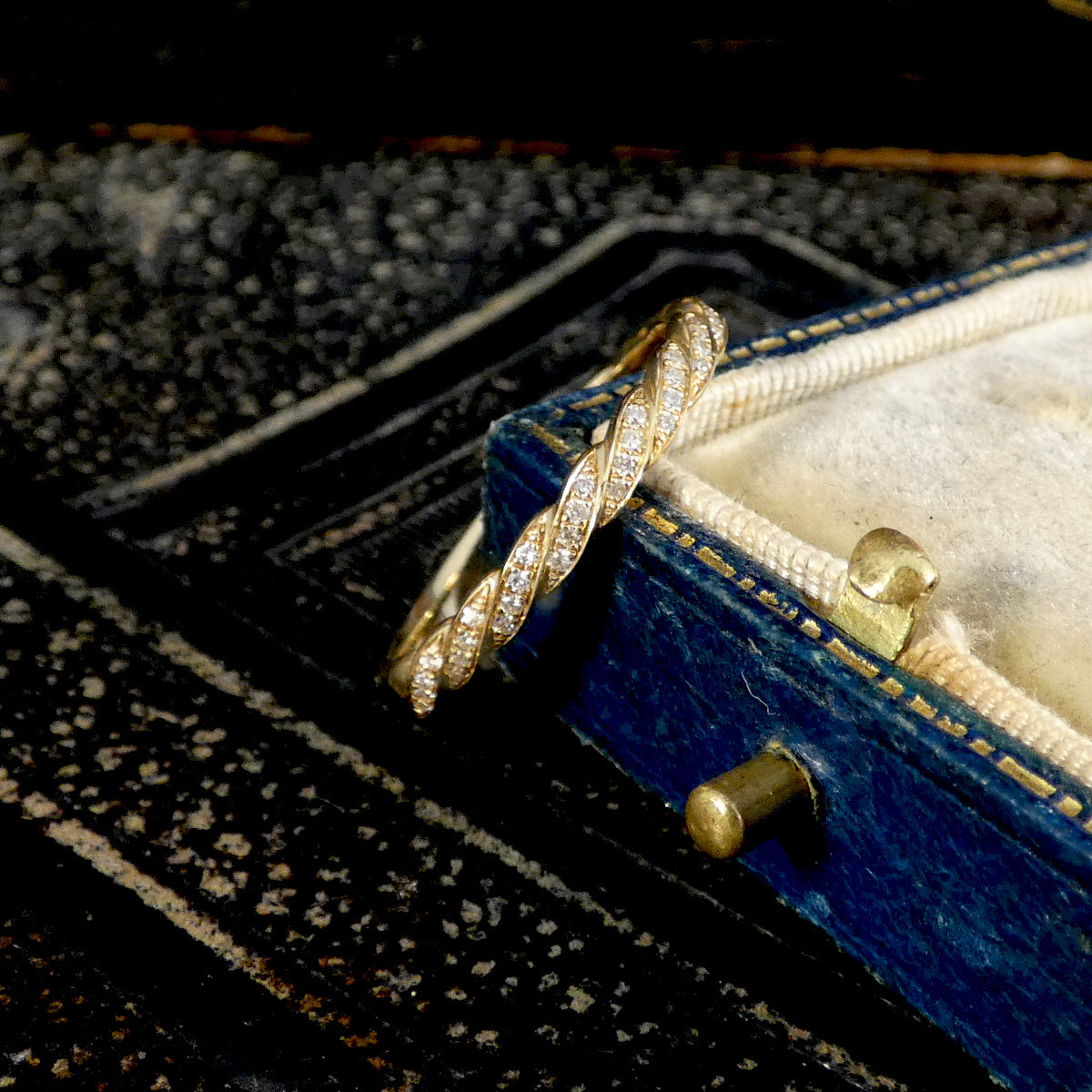 Gold ring with diamond accents on a blue jewelry box