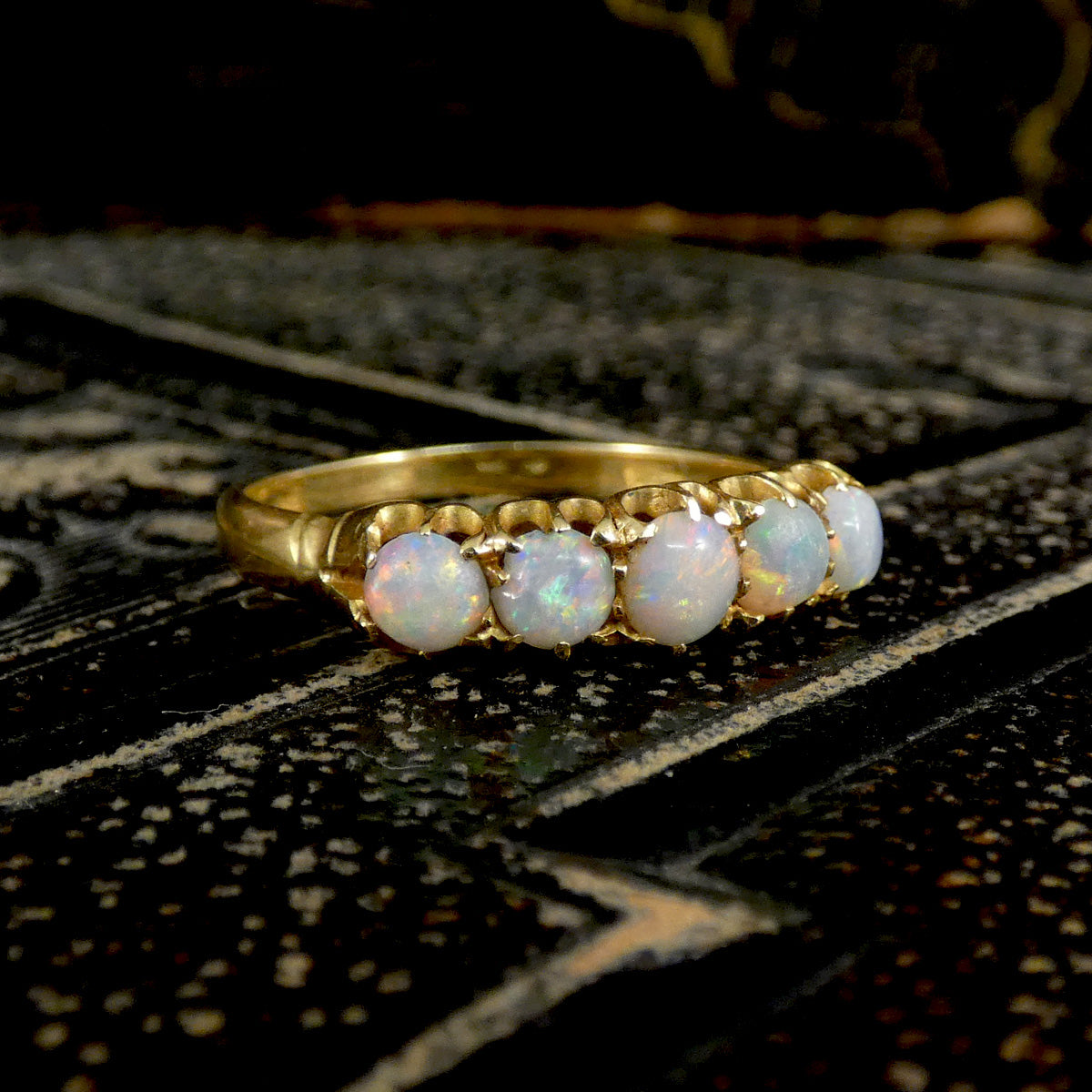 Gold ring with opal stones on a textured dark surface