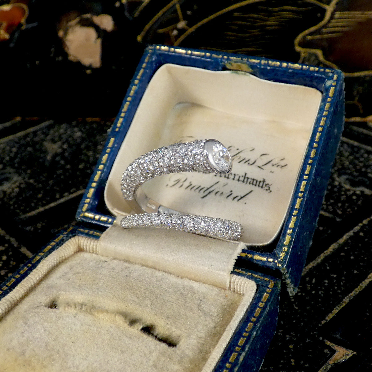 A unique diamond set snake like ring shown in an antique box.